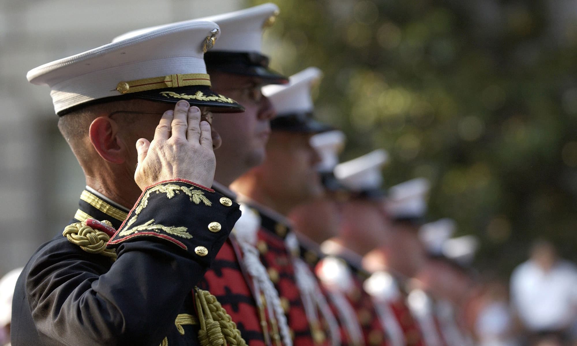 Marine Corps officers in dress uniform saluting in formation